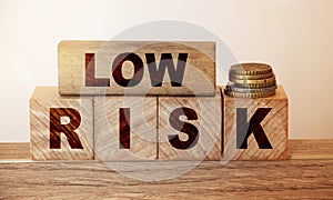 Low risk on wooden blocks and coins stack on wooden table. Rrisk concept in business or investment