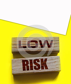 Low risk words wooden blocks on yellow. Business investment risks concept