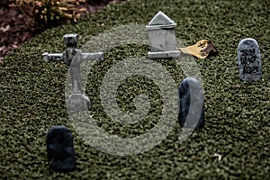 Low-saturation closeup of tiny model gravestones in a graveyard