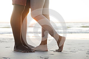 Low section of african american couple embracing on beach at sunset