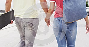 Low section of african american young couple holding hands walking together on the promenade