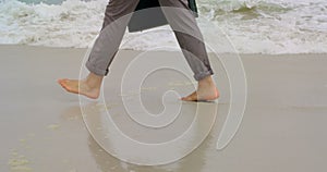 Low section of Businessman walking barefoot with briefcase on the beach 4k