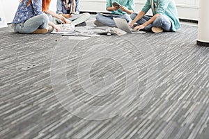 Low section of businesspeople working on floor in creative office