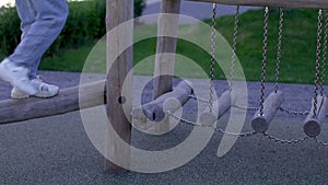 Low section of child playing obstacle course on wooden equipment
