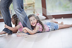 Low section of father dragging girls on hardwood floor