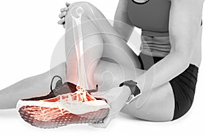 Low section of female athlete suffering from ankle pain on white background photo