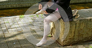 Low section of female ballerina wearing ballet shoe in the park 4k