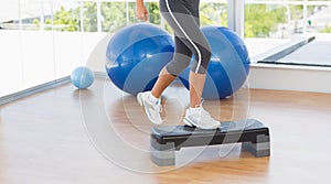 Low section of a fit woman performing step aerobics exercise