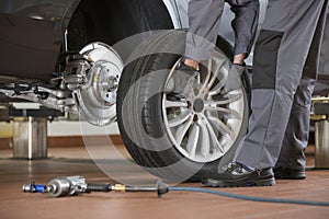 Low section of male mechanic repairing car's tire in repair shop