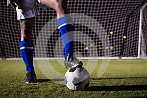 Low section of male soccer player standing with ball on field