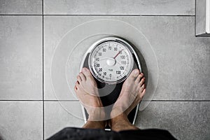 Low section of man standing on weight scale