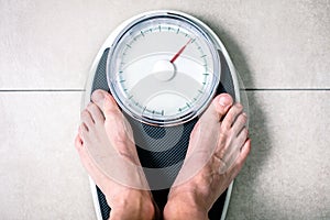 Low section of man standing on weight scale