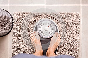 Low section of man standing on weight scale