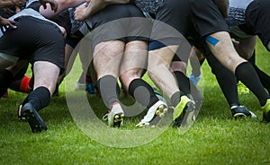 Low Section Of People Playing Rugby On Grassy Field. Rugby players in scrum. Team sport