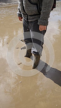 Low section of a person ankle-deep in a muddy puddle