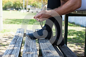 Low section of rugby player tying shoes on bench