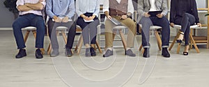 Low section shot of legs of group of business people sitting on chairs if office