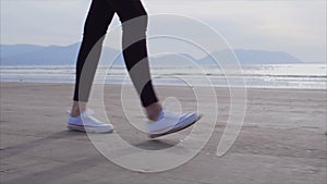 Low section slow motion of woman walking on wet shore