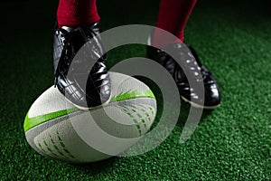 Low section of sportsperson stepping on rugby ball photo