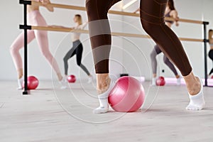 Low section view at row of women stretching feet using fitness ball