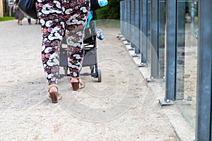Low Section of Woman with colorful trousers and shoes with wedge heel pushes stroller, floor recording