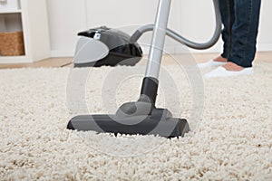 Low section of woman vacuuming floor