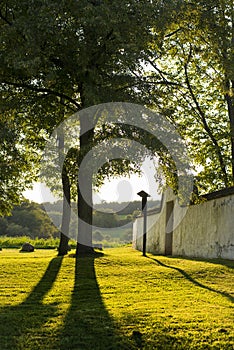 Low setting sun in green park casting long shadows. Chapel of Gods mother by the Veveri castle Brno Czech Republic