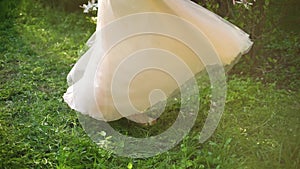 Low shot of woman in elegant dress turning around in green garden in slow motion