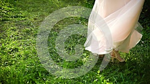 Low shot of woman in long dress turning around on green grass in slow motion