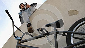 Low shot young man listening to music while sitting near his bicycle