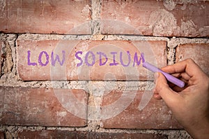 Low Sodium. Text written with purple chalk on a red brick background