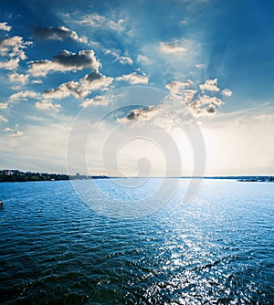sunset in dramatic clouds over blue water in river