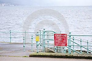 Low tide area subject to tidal flooding warning sign at harbour wall