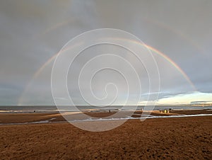 Low tide at beach with double rainbow