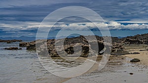 Low tide. Many attached mollusks can be seen on the exposed rocks.