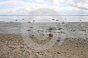 Low tide on the ocean and boats aground on the muddy sand