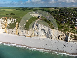 Low tide period and aerial view on ocean bed and chalk cliffs of Porte d`Aval arch in Etretat, Normandy, France. Tourists photo