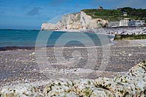 Low tide period and view on ocean bed and chalk cliffs of Porte d`Aval arch in Etretat, Normandy, France. Tourists destination photo