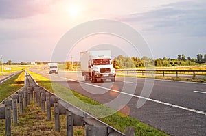 A low-tonnage commercial refrigerated van transports perishable products in the summer on a country road against the