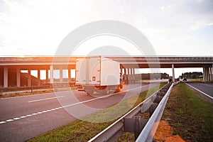 A low-tonnage commercial refrigerated van transports perishable products in the summer on a country road against the photo