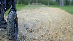 Low View Close-up of the wheels of a baby stroller in autumn or spring, riding on leaves and puddles. Carriage Truck