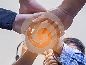 A low view of many people`s hands in a circle together with sunlight effect. Concept of unity and together