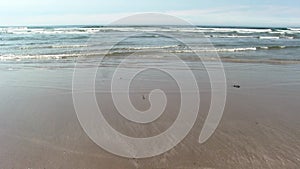 Low View Of Ocean Waves On Sand Beach With Blue Sky And White Clouds