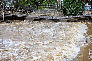 A low view of the river flowing violently past a broken wooden bridge