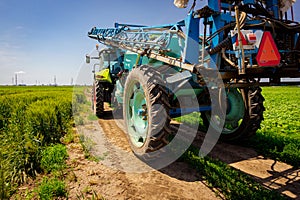 Low view of tractor with mounted sprayer as travel on dirty road