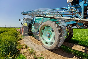 Low view of tractor with mounted sprayer as travel on dirty road