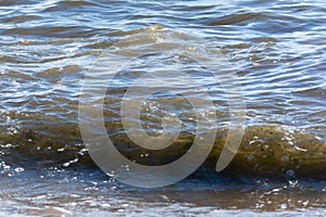 Low view of waves breaking on the beach sand on a cloudy day