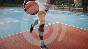 Low view of young afro American athlete has basketball training. Caucasian guy dribbling a ball, throwing and scoring on