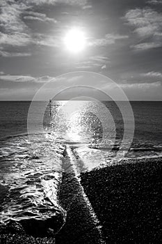 The low winter sun shining on the sea and sea breaks on the beach