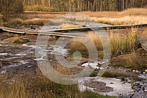 Low wooden trail over drying water stream.